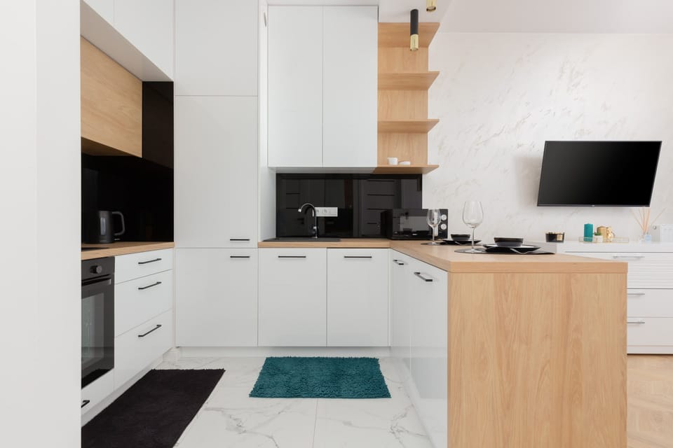 A kitchen with a dining area, including a black and white color scheme and wooden shelves.