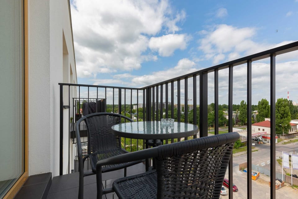 A spacious balcony featuring a table and two chairs, overlooking greenery.