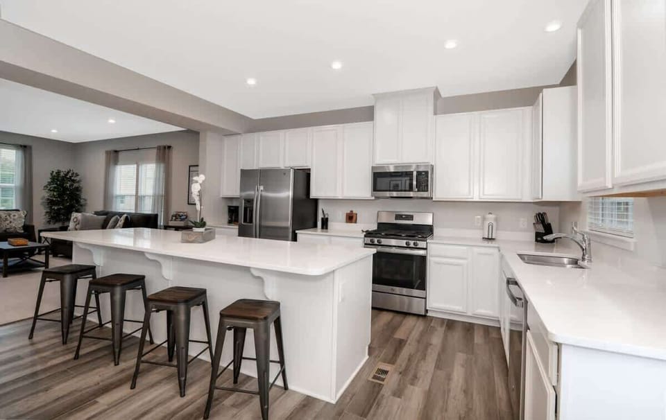 This stunning kitchen is a chef's dream, featuring top-of-the-line stainless steel appliances, sleek cabinetry, and beautiful countertops. The large center island offers ample space for meal prep and dining, while the open layout makes entertaining e