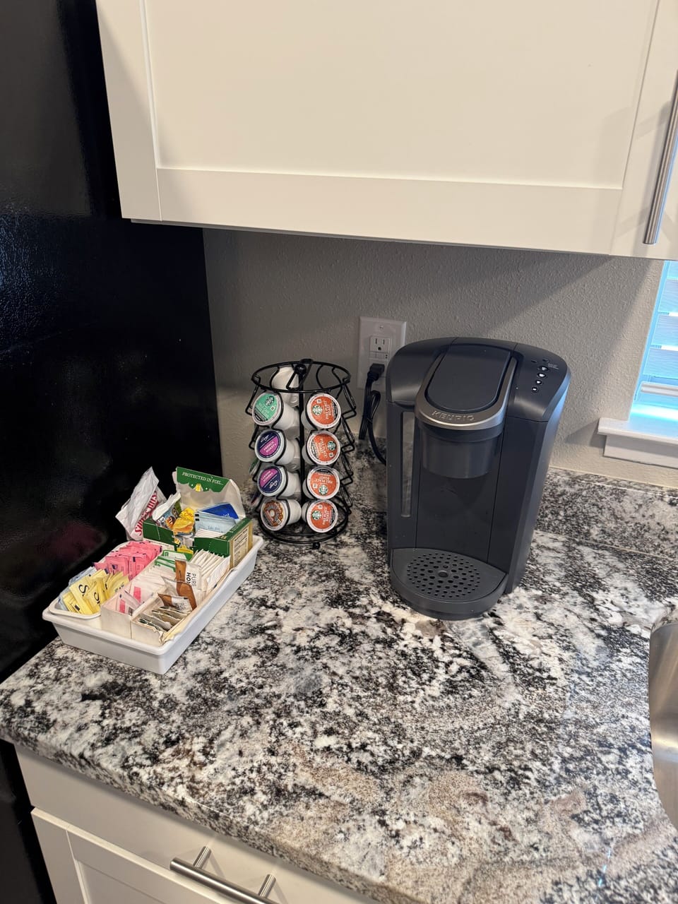 Keurig coffee maker with complementary pods, sweeteners and creamers.