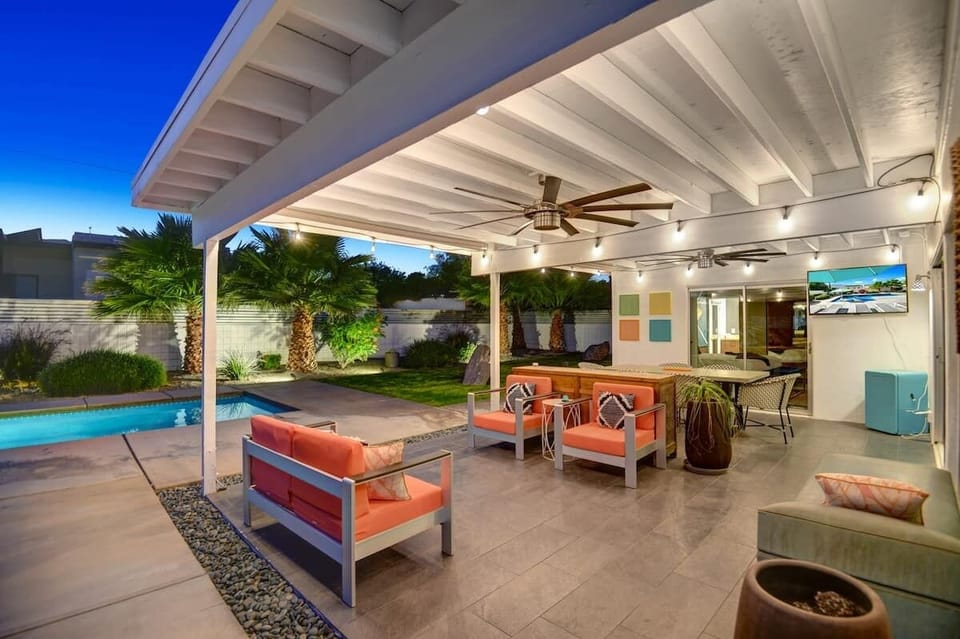 Covered outdoor lounge with lighting, comfortable seating, and an outdoor TV.
