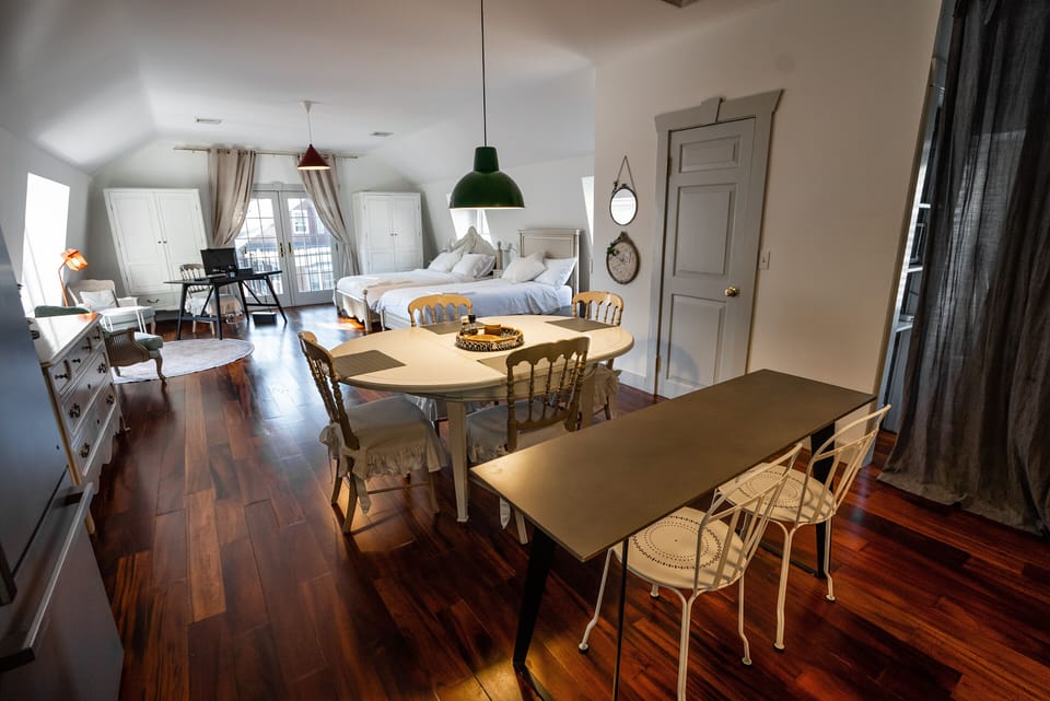 Dining table with view of sitting area, two beds, and work station
