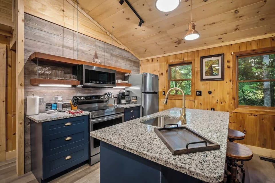 Warm and inviting kitchen with granite countertops, stainless steel appliances, and rustic wood accents. Fully equipped for home-cooked meals in a cozy, cabin-style setting.