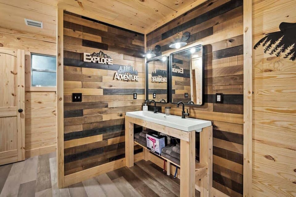 Rustic-modern bathroom with double vanity, wood-accented walls, and adventure-themed decor for a warm, cabin-inspired feel.