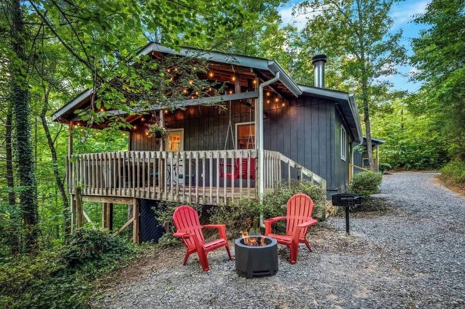 Peaceful cabin escape with a wraparound deck, fire pit, and twinkle lights nestled in the heart of the forest.