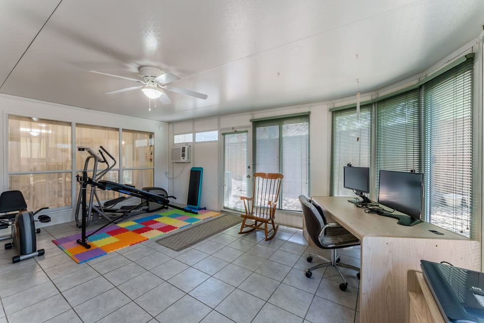 Large gameroom, with workout equip, work desk, and access to backyard.