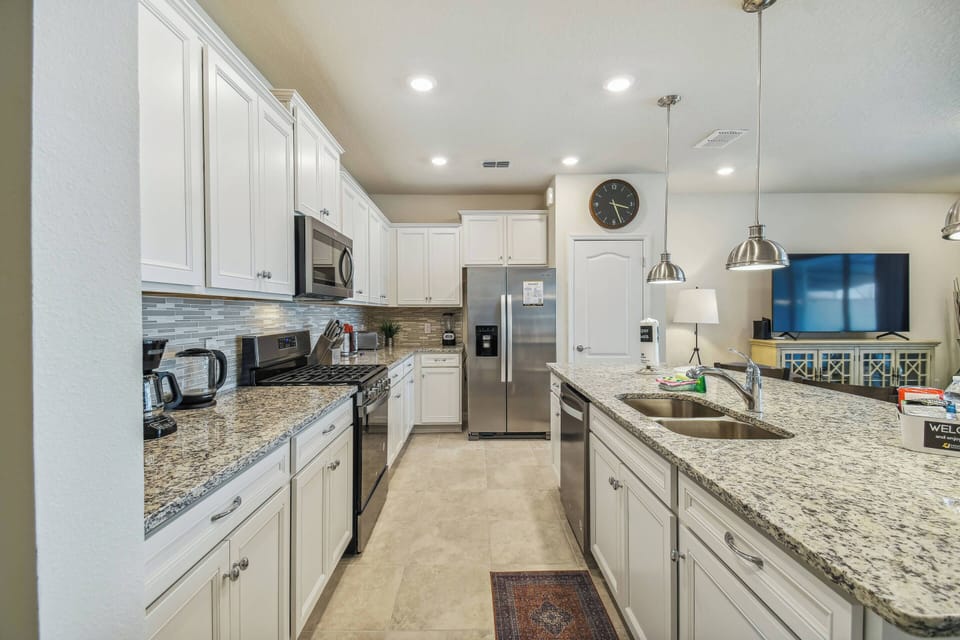 This beautiful kitchen boasts granite countertops and white cabinetry, creating a bright, inviting atmosphere. With stainless steel appliances and modern lighting, it's perfect for preparing delightful meals with ease.