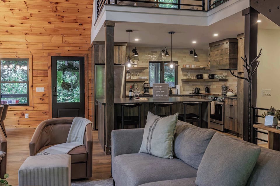River Run's family room was designed for togetherness — West Elm and Pottery Barn furnishings, a stove fireplace, and large slider doors opening to the sounds of the Ellijay River.