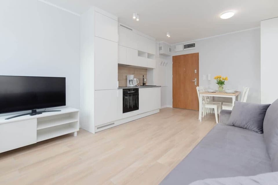 A spacious open-plan living area with a dining table, sofa, and access to the kitchen.
