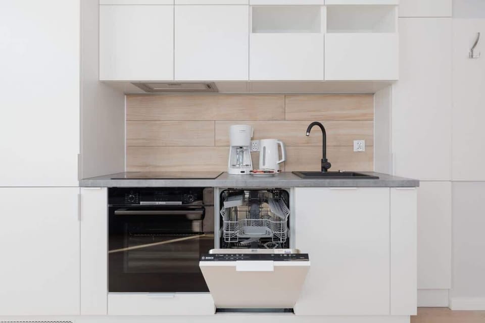 A sleek kitchen with white cabinetry, a black countertop, and high-end appliances for convenient cooking.
