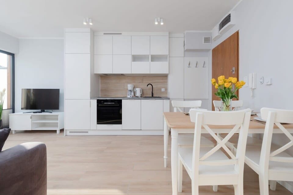 An open-plan kitchen and dining area with a white dining set and modern appliances, perfect for hosting meals.
