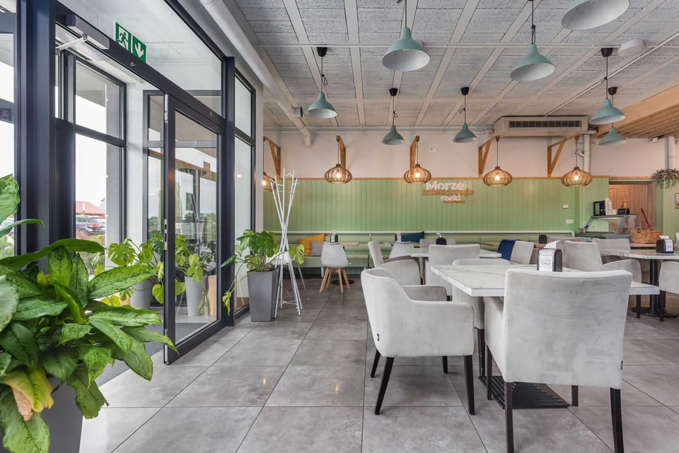 Another dining space with large windows, ample greenery, and contemporary furniture, ideal for group gatherings.
