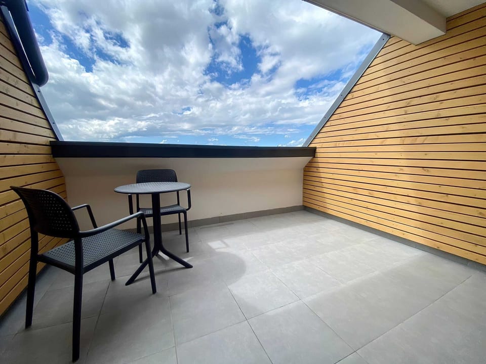 A spacious terrace with outdoor seating, wooden paneling, and stunning views of the sky and surroundings.
