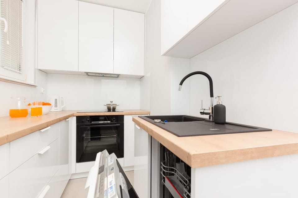 A sleek kitchen with white cabinetry, wooden countertops, and modern appliances for a fully equipped cooking space.
