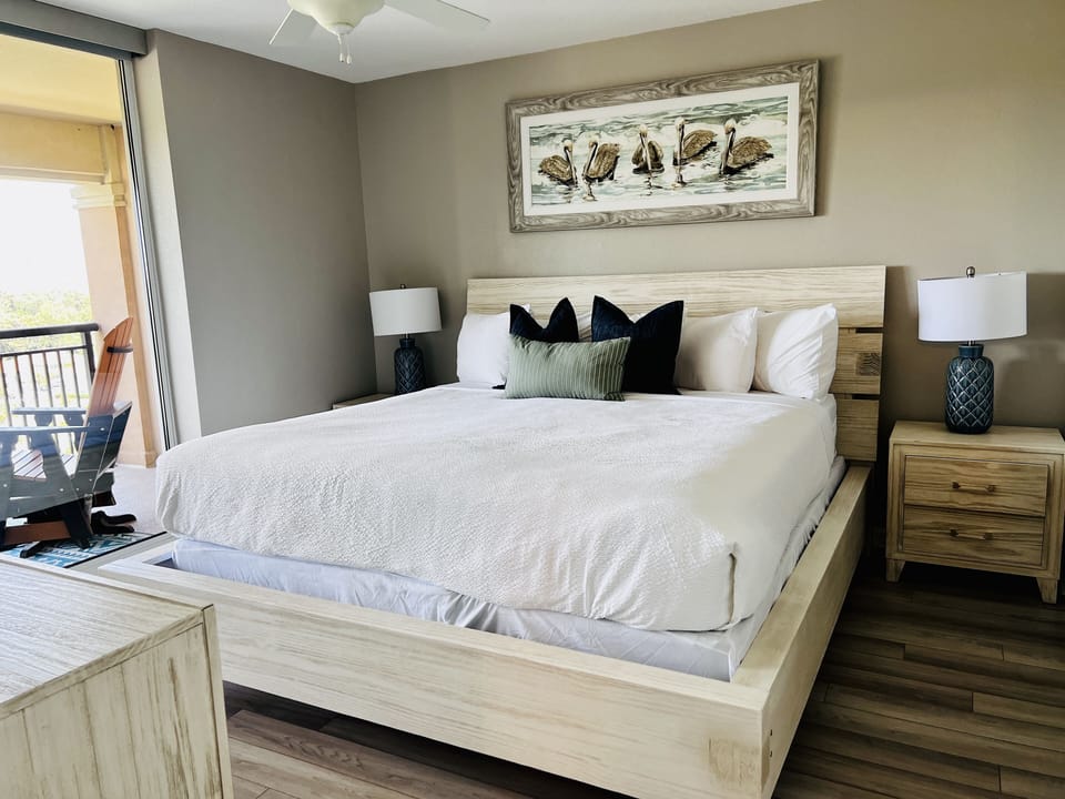 Sink into crisp white linens and coastal comfort in your beautifully appointed bedroom, complete with ocean-themed artwork and private balcony access.
