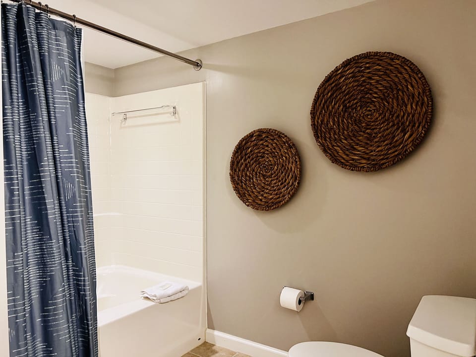 Relax in your pristine bathroom with thoughtful details like woven basket art and modern fixtures for your comfort.