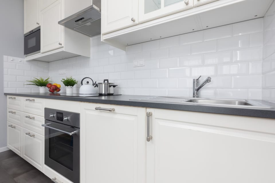 A closer view of the kitchen, highlighting white cabinets, a sleek countertop, and practical appliances.
