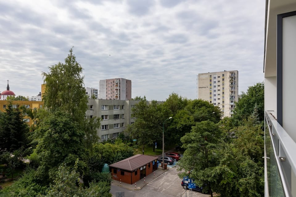 A view from the balcony, overlooking a mix of greenery and urban surroundings.
