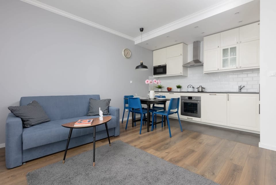 An open-plan living and dining area with wooden floors, blue and gray furniture, and plenty of space for relaxation.
