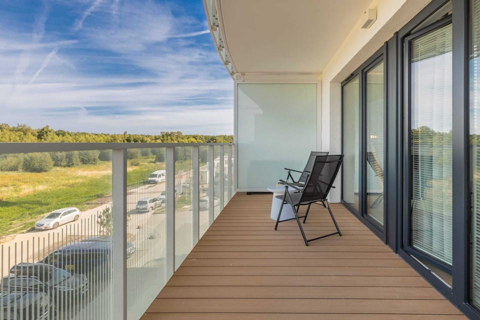 A spacious balcony with outdoor seating and a panoramic view of the surrounding greenery.
