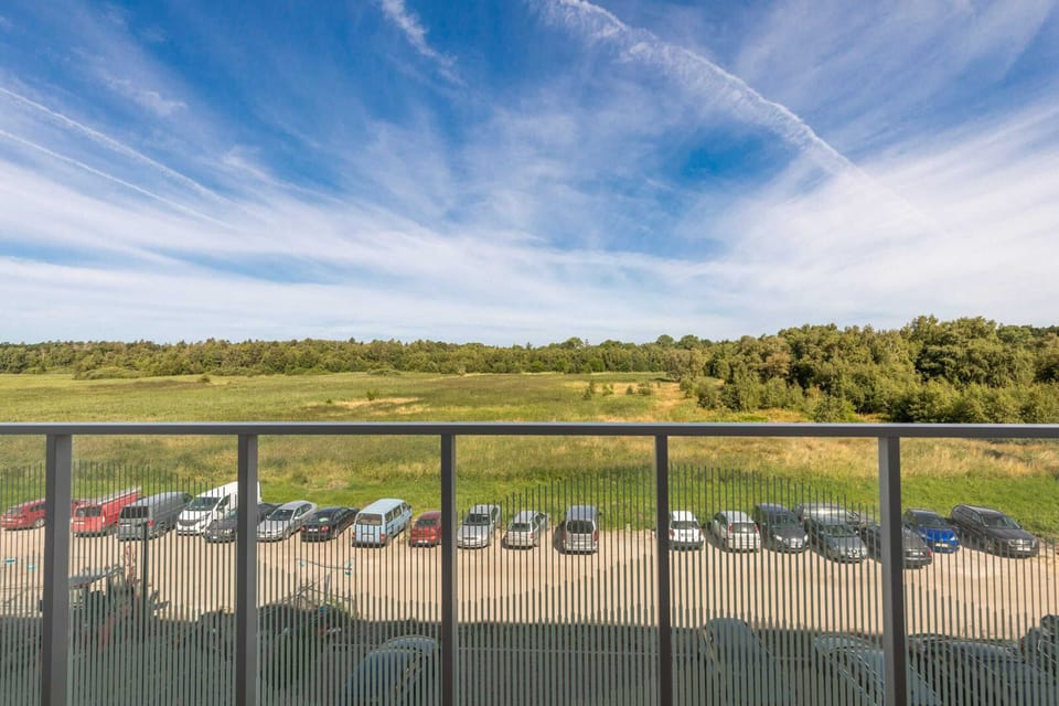 A scenic balcony view overlooking a green field and blue skies, perfect for enjoying the outdoors.
