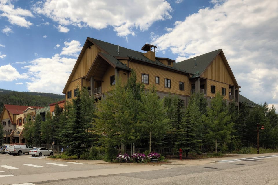 A charming alpine-style building nestled among evergreens in a scenic mountain community, offering convenient access to local shops and natural beauty.