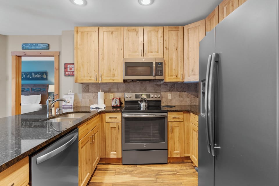 Your fully equipped kitchen features granite countertops, stainless appliances, and warm wood cabinets—perfect for preparing meals during your mountain getaway.