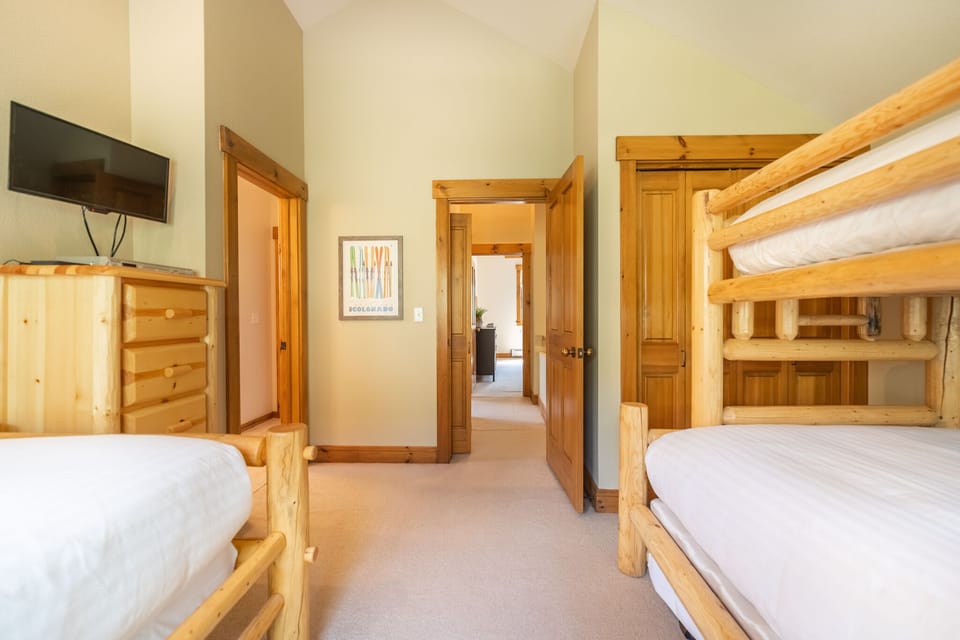 Guest bedroom with twin-over-full bunk bed with twin trundle, stand alone twin size bed and flat screen TV.