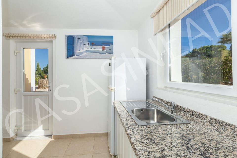 Kitchen in Casa Sinead with granite worktops, stainless steel sink, and direct access to the garden terrace, allowing guests to enjoy Algarve sunshine while preparing meals in this well-equipped holiday villa