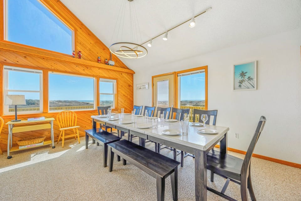 Gather around this spacious dining table where your meals come with breathtaking natural views through floor-to-ceiling windows. The vaulted ceilings and warm wood accents create an inviting space for memorable group dinners.