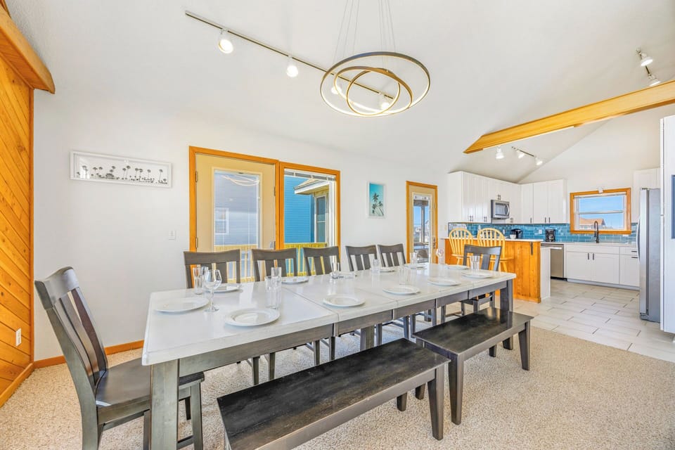Gather around this spacious dining table where your group can share meals, stories, and laughter together. Natural light pours in through large windows, while the open kitchen makes hosting easy and fun.