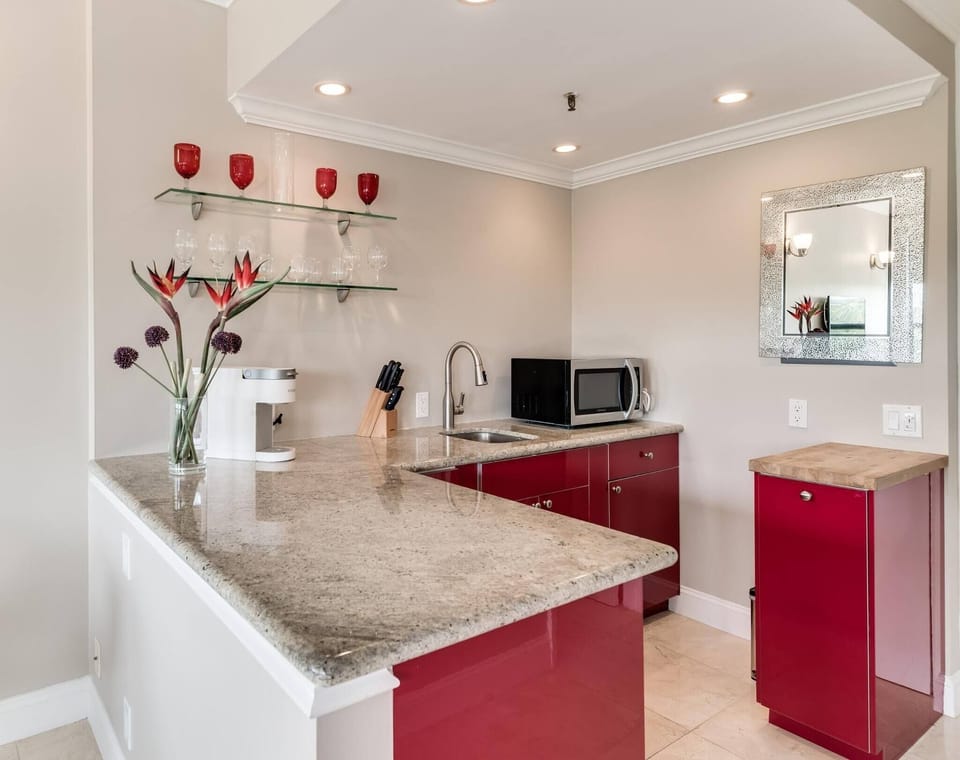 Kitchenette with microwave, mini fridge, Keurig coffee maker, glasses, plates, and cutlery
