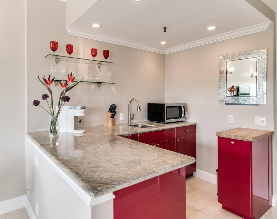 Kitchenette with microwave, mini fridge, Keurig coffee maker, glasses, plates, and cutlery
