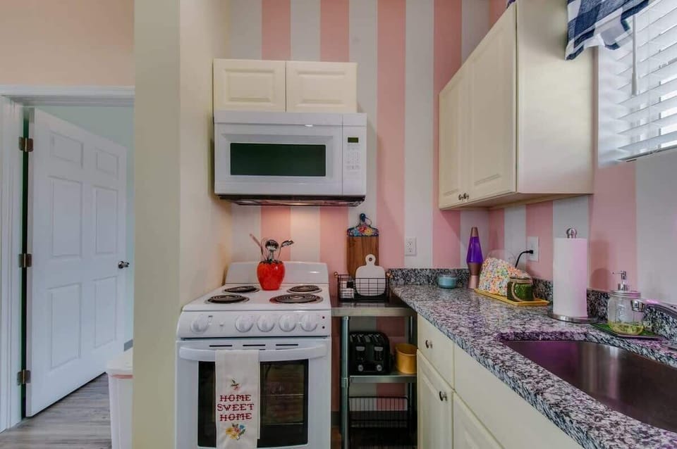 Pink striped kitchen with full appliances keeps the whole group fed and connected, the cook never gets stuck solo while the crew hangs in the open living room