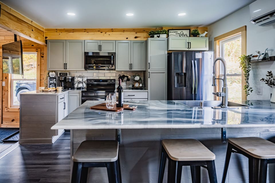 From morning coffee to holiday dinners, this beautifully designed kitchen has everything you need. Featuring high-end stainless steel appliances, and a spacious island with seating, it's the perfect place to gather, cook, and connect.

Prepare your favorite meals with ease, enjoy a glass of wine while dinner is in the oven, or pull up a stool and chat while the chef works their magic. Thoughtfully stocked with cookware, dishes, and essentials, this kitchen combines modern convenience with warm farmhouse charm—making every meal feel like home.