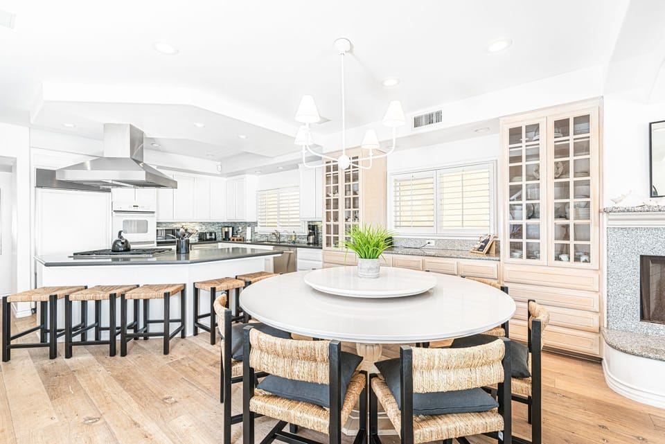Beyond the living area is the primary dining table, with seating for 8 and kitchen w/ bar seating beyond.
                