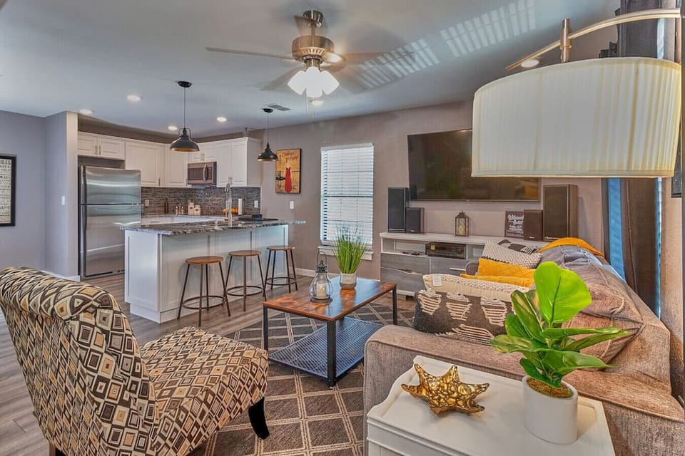 The living room is furnished with a large television and a ceiling fan.