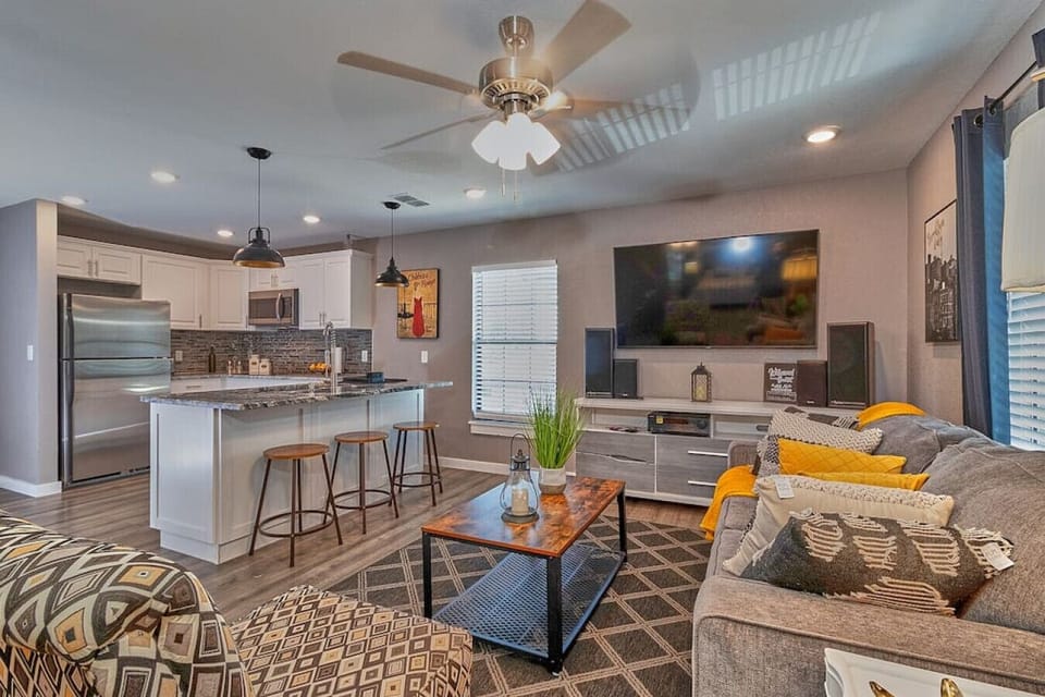 The living room is furnished with a large television and a ceiling fan.