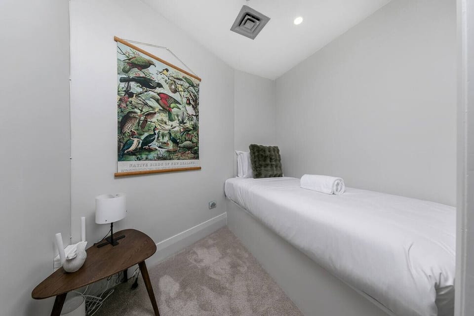 The cosy second bedroom features a comfortable single bed and a charming New Zealand native birds print -- a peaceful penthouse nook in the heart of the Viaduct Marina.