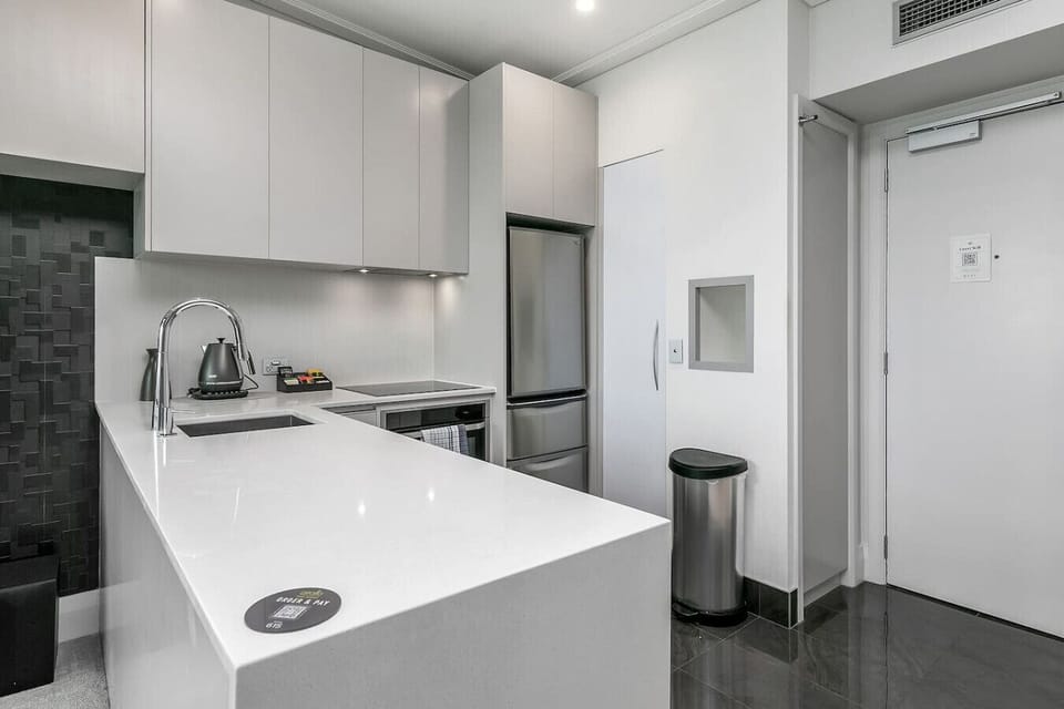 Every detail in this Sebel penthouse kitchen has been considered -- from the stone benchtops and sleek cooktop to the generous counter space perfect for morning coffee prep.