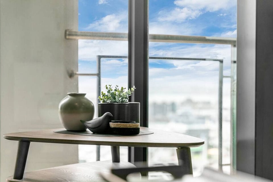 Thoughtful touches define this Sebel penthouse -- curated ceramics and greenery catch the harbour light on a mid-century side table, framing the sky beyond.