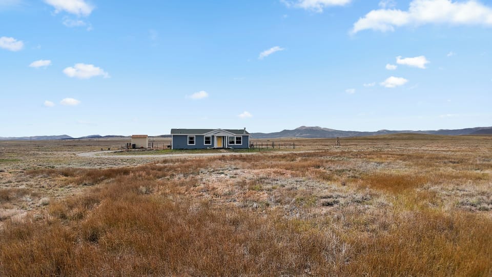 Secluded modern cabin set against open prairie and mountain backdrops