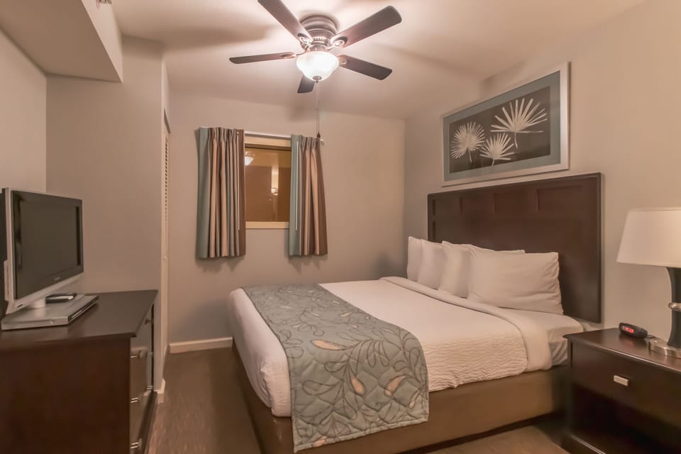 Unwind in your cozy bedroom featuring plush bedding, gentle ceiling fan, and modern amenities for a perfect night's rest.
