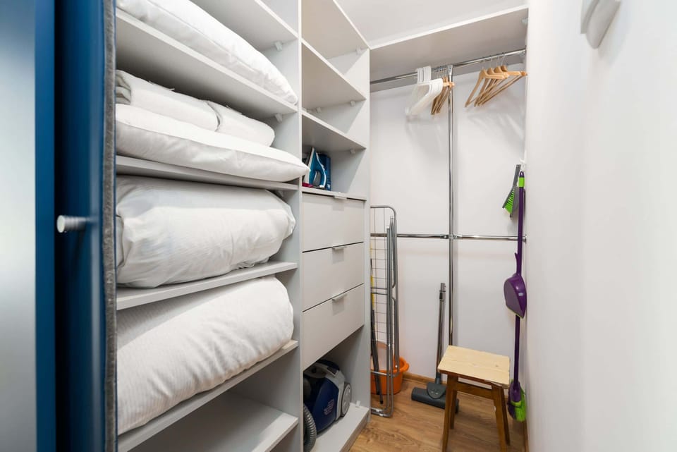 A well-organized wardrobe or storage room with shelves stocked with linens and clothing space.
