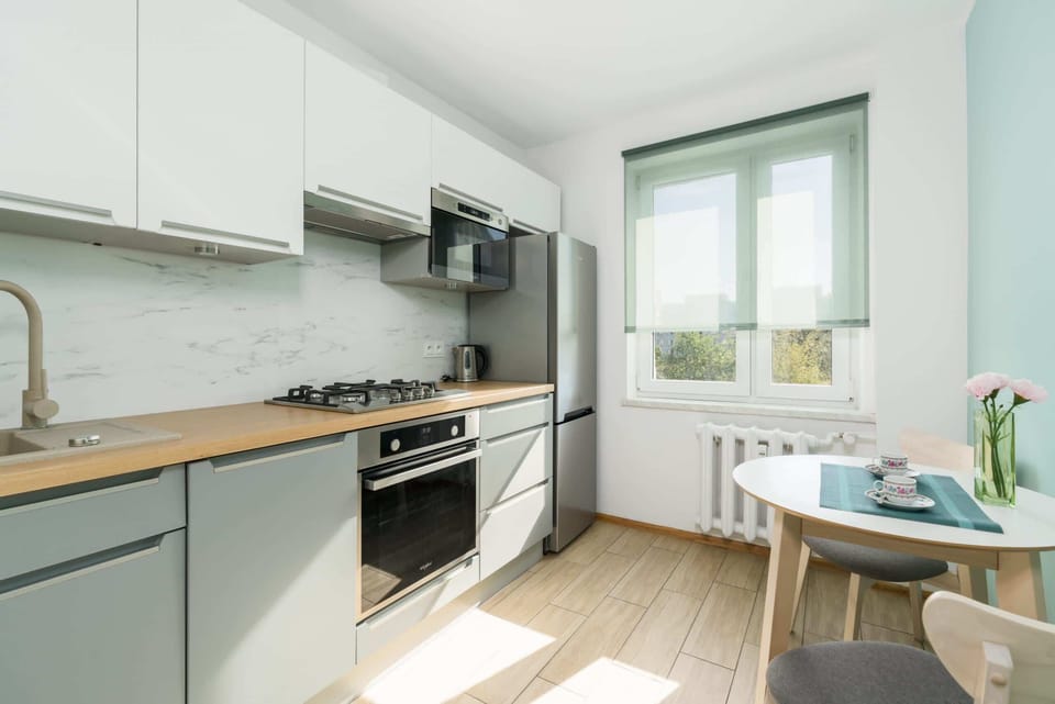 A functional kitchen with white cabinetry, a gas stove, and a small dining table near a window for natural light.
