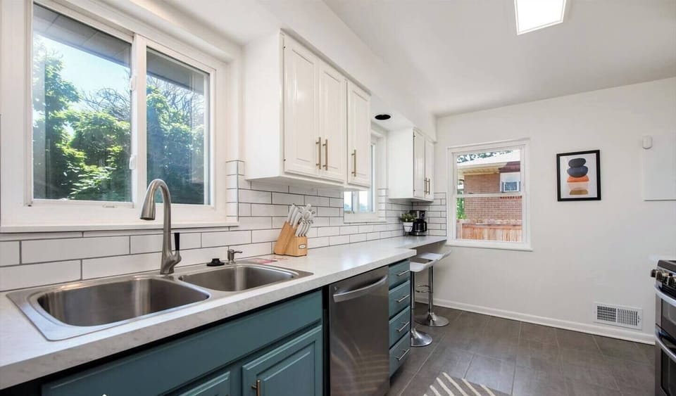 - Double sink, quartz counters, and tile accents combine beauty and function
- Bar stools sit under the window nook, perfect for sipping coffee or wine
- Fresh air and leafy views stream in through sunlit corner windows