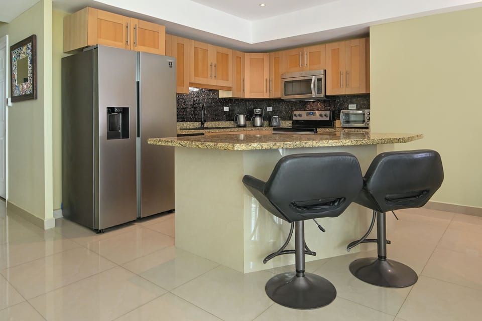 Your fully-equipped kitchen features stainless steel appliances, granite countertops, modern cabinets, and bar seating—perfect for cooking meals together and gathering over morning coffee.