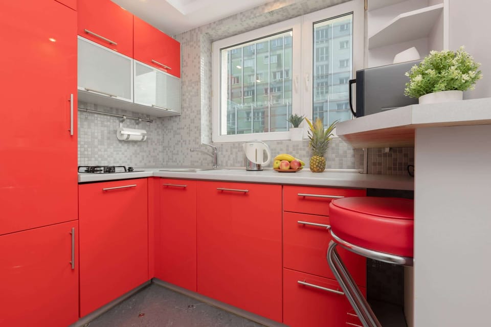 A sleek kitchen with bold red cabinetry, modern appliances, and a compact layout, perfect for meal preparation.
