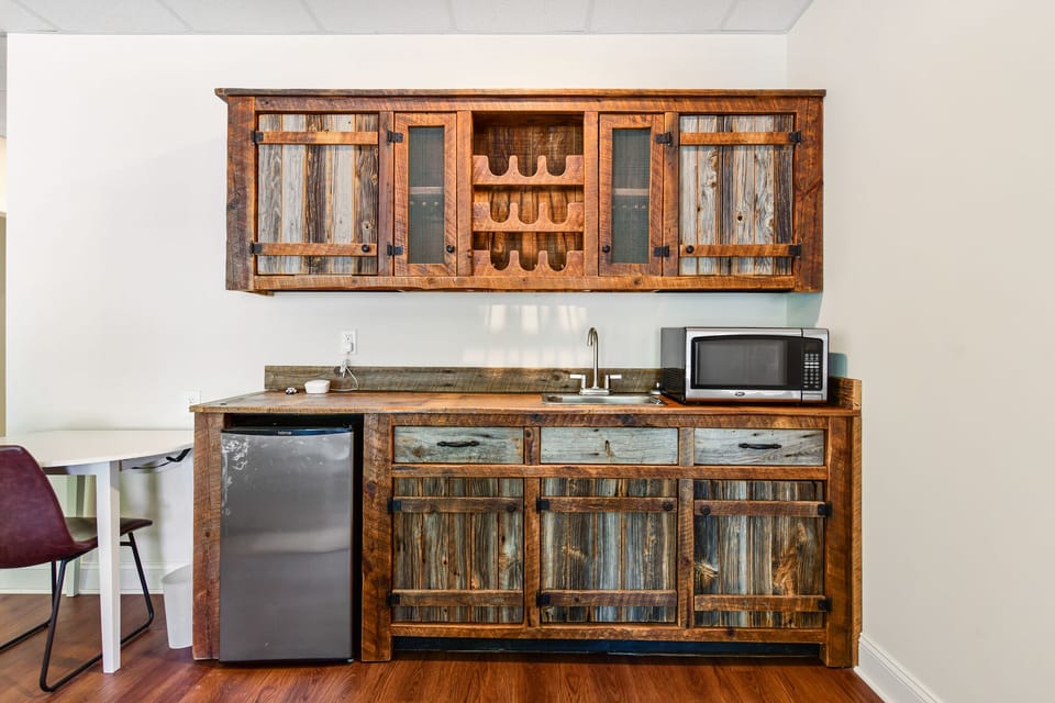 Basement bar with sink microwave, refrigerator and work table.