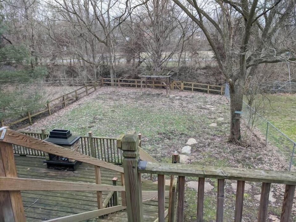 Back yard from upper deck. Split rail fence is lined with wire mesh. 